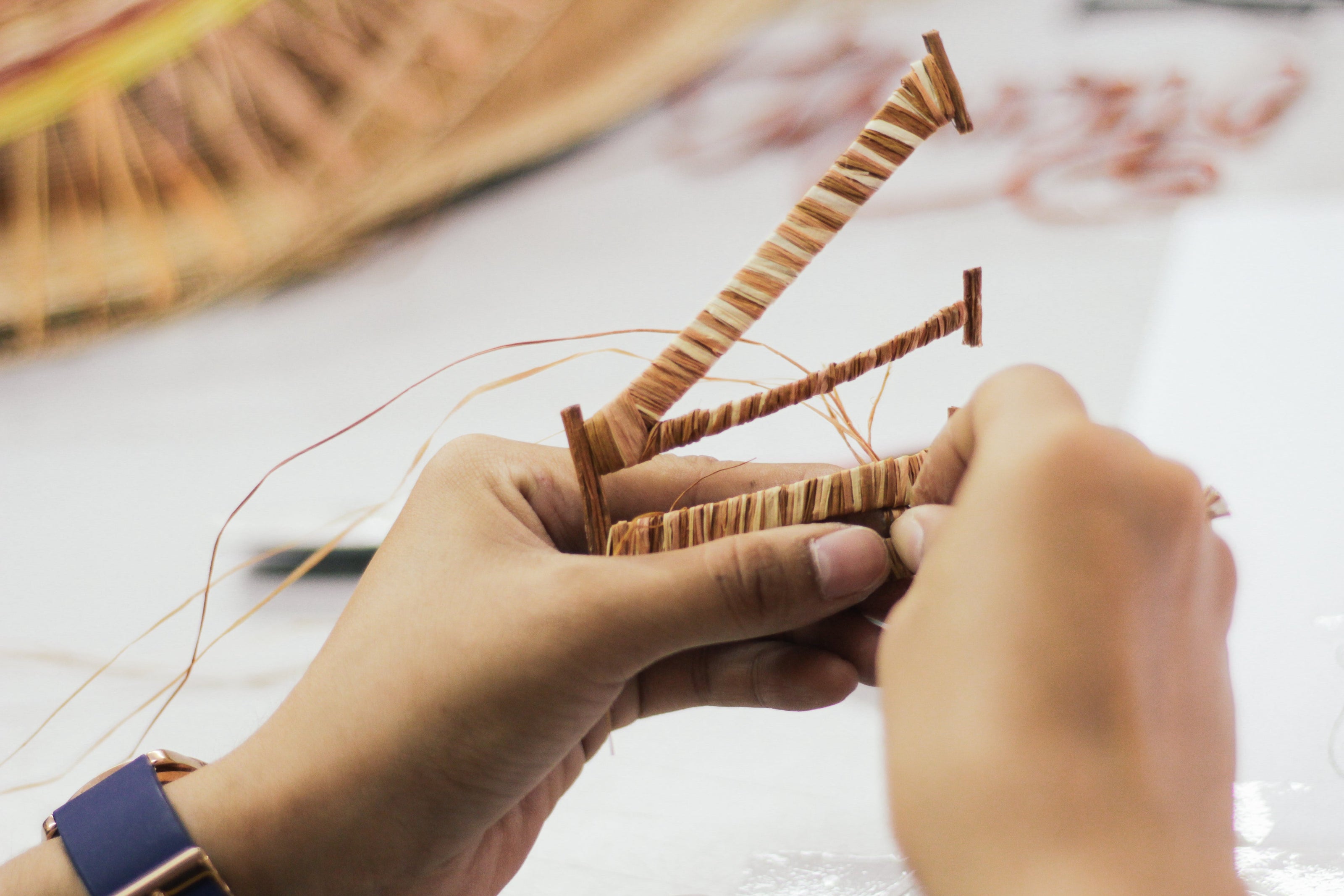 Close-up of hands working with yarn and a needle on a light background